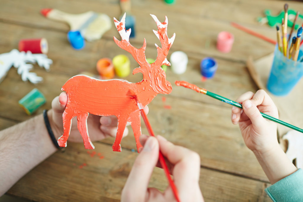 Child and adult painting a deer